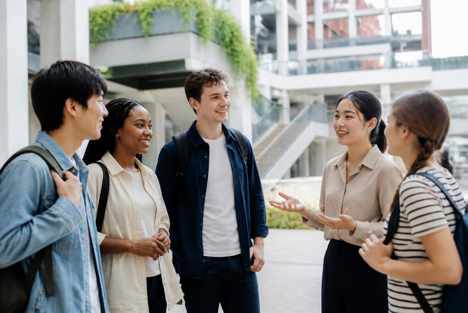 University-age international students in conversation with a Chinese coordinator on a modern campus.